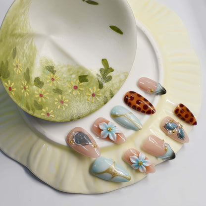 Fashionable press on nails featuring blue florals, gemstone accents and leopard inspired artwork.