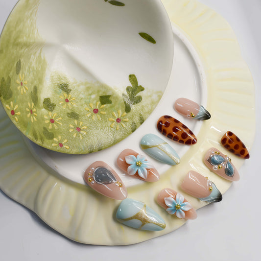 Fashionable press on nails featuring blue florals, gemstone accents and leopard inspired artwork.