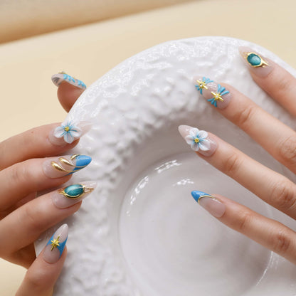 Handmade ocean blue press on nails with gold starfish charms, floral details and gemstone accents on nude base.