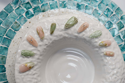 Elegant sage green and nude press on nails with gold metallic detailing and pearl accents.