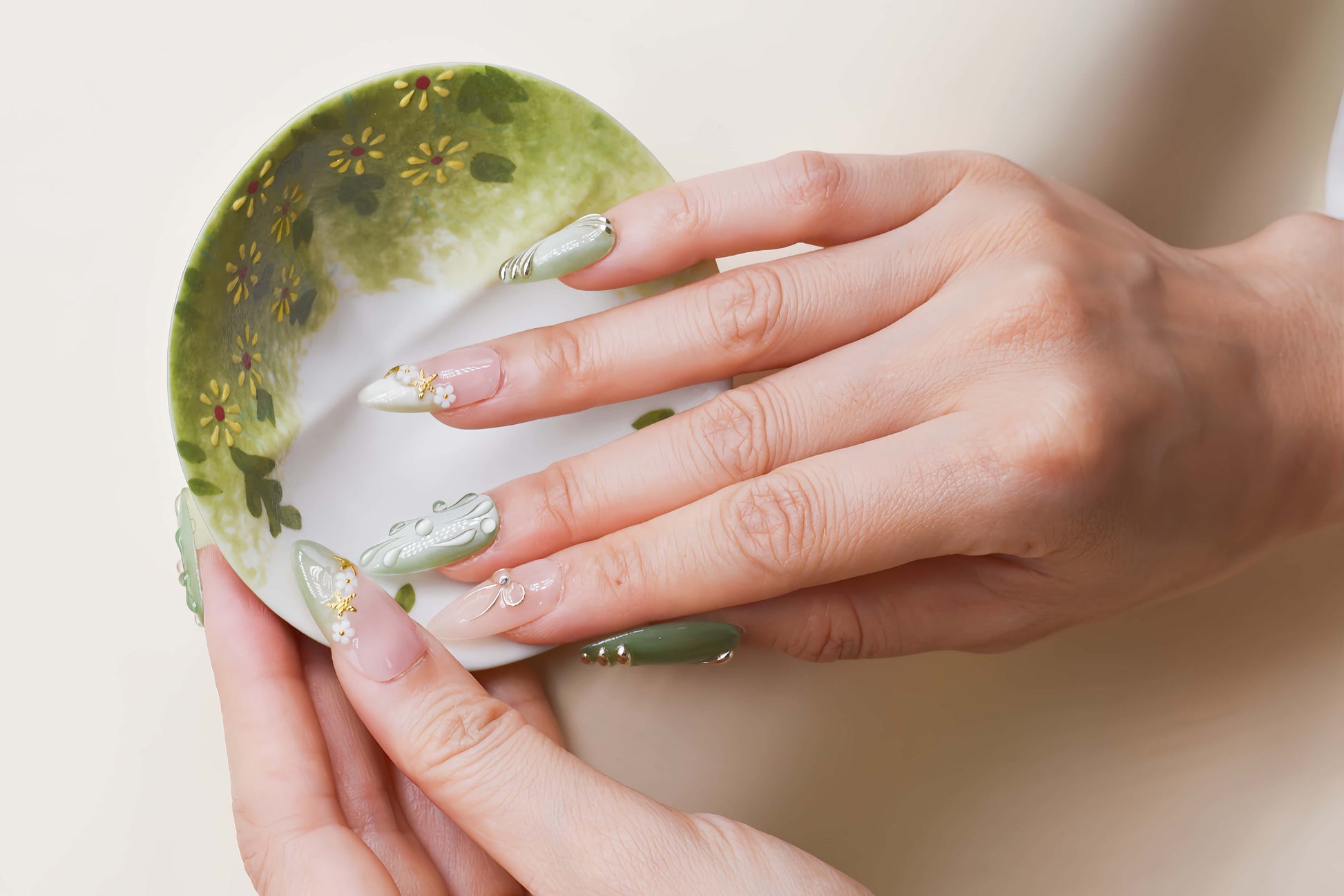 Elegant sage green and nude press on nails with gold metallic detailing and pearl accents.