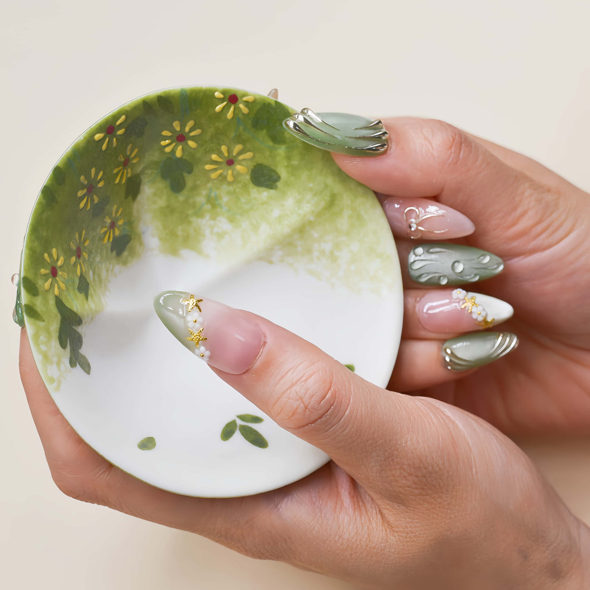 Elegant sage green and nude press on nails with gold metallic detailing and pearl accents.