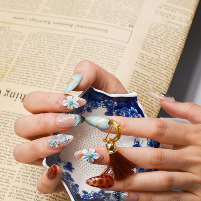 Fashionable press on nails featuring blue florals, gemstone accents and leopard inspired artwork.
