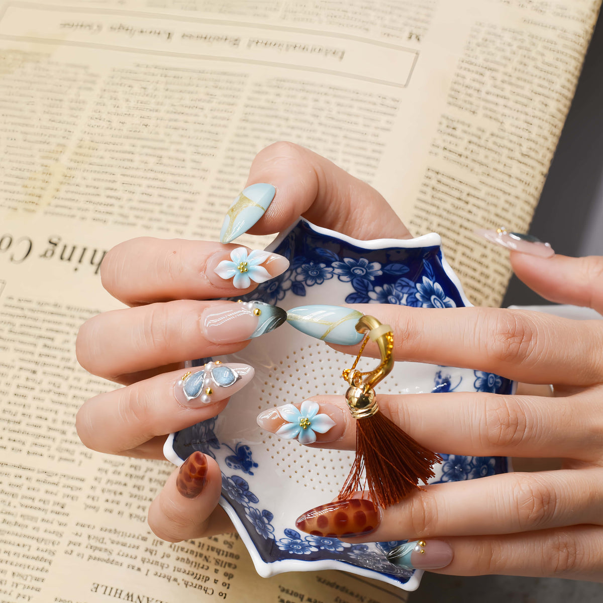 Fashionable press on nails featuring blue florals, gemstone accents and leopard inspired artwork.