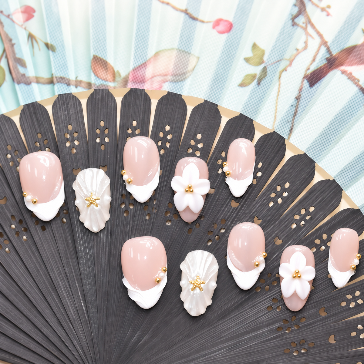 Pearl Tide Blossom blush press-on nails with white petals, pearls and gold starfish details — styled product photograph.
