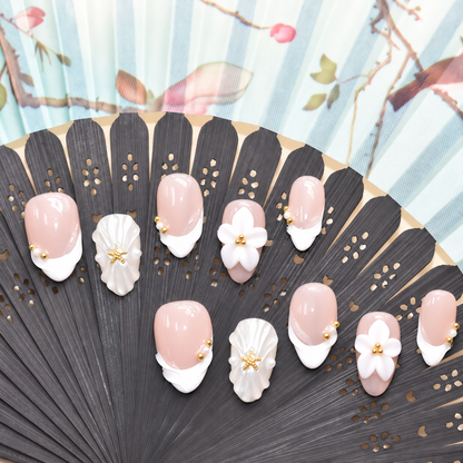 Pearl Tide Blossom blush press-on nails with white petals, pearls and gold starfish details — styled product photograph.