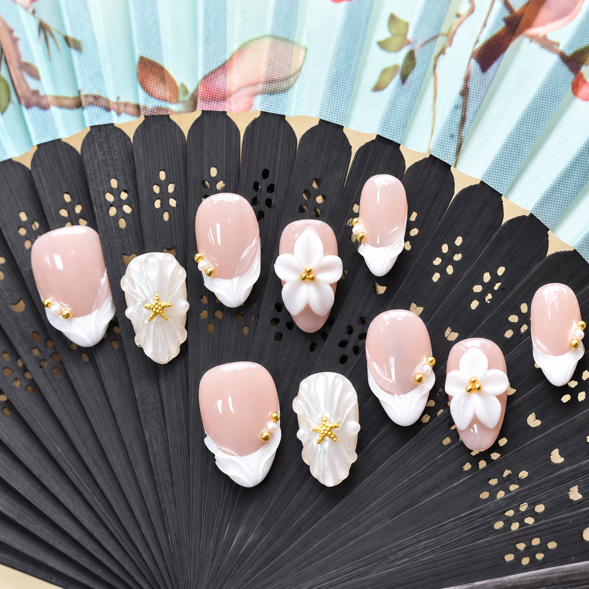 Pearl Tide Blossom blush press-on nails with white petals, pearls and gold starfish details — styled product photograph.