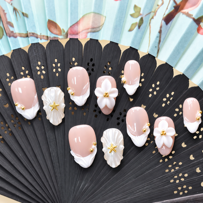 Pearl Tide Blossom blush press-on nails with white petals, pearls and gold starfish details — styled product photograph.