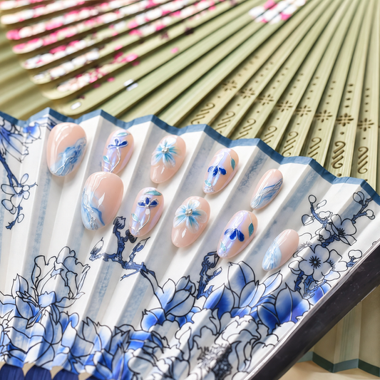 Blue Porcelain Bloom nude press-on nails with cobalt flowers, turquoise leaves and silver linework — styled product photograph.