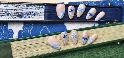 Blue Porcelain Bloom nude press-on nails with cobalt flowers, turquoise leaves and silver linework — styled product photograph.