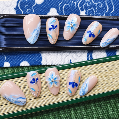 Blue Porcelain Bloom nude press-on nails with cobalt flowers, turquoise leaves and silver linework — styled product photograph.