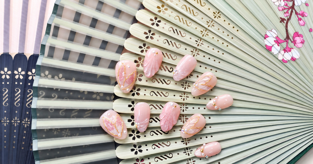 Rose Gold Leaf Veil peach press-on nails with translucent leaves, pearls and fine gold outlines — styled product photograph.