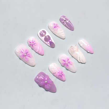 Lilac ombre glitter press on nails with 3D flowers, pearl centers, and bow accents – medium almond shape from Candy Bloom Collection.
