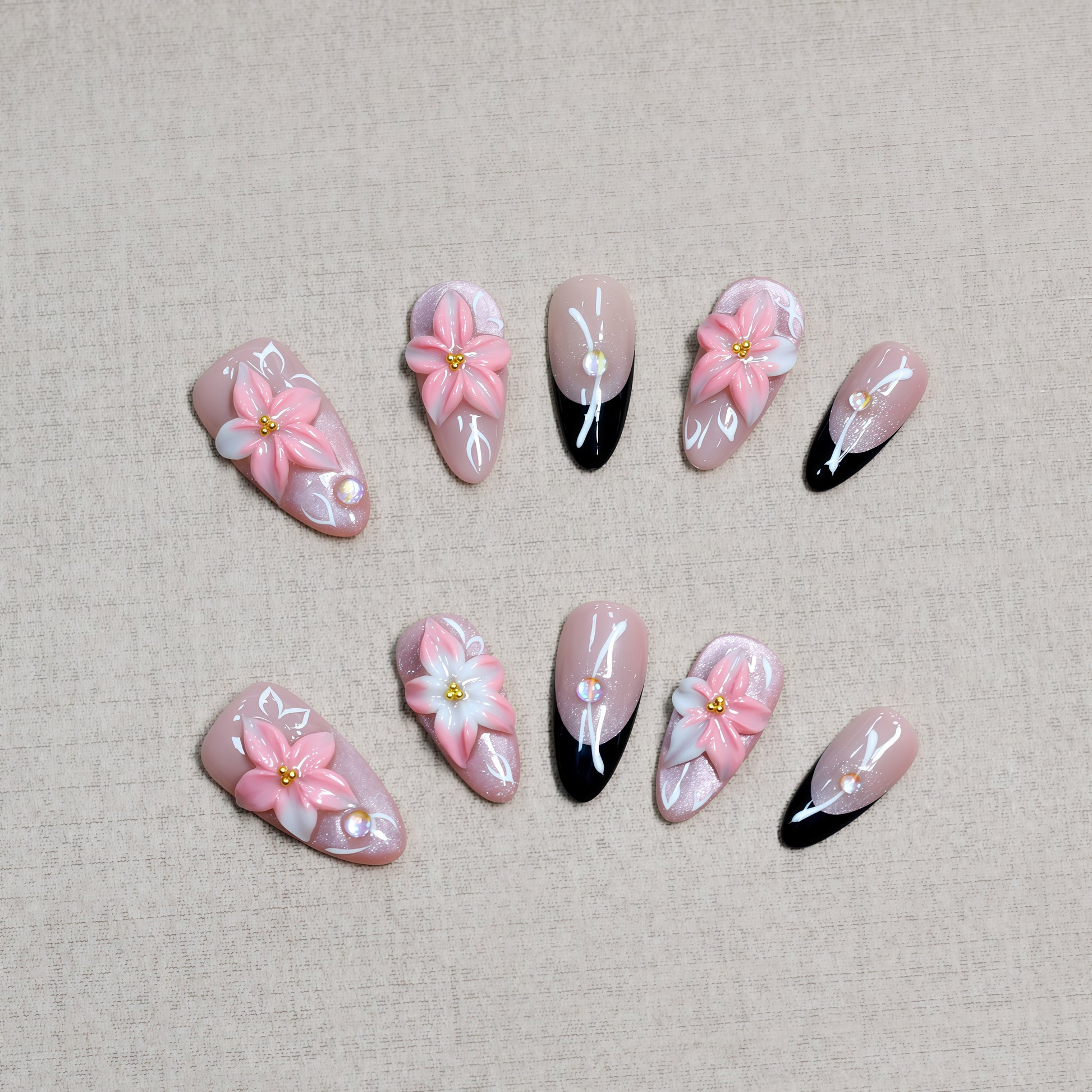 Luxury pink floral press-on nails with 3D flower design, pearl embellishments, and black French tip accents displayed on beige textured background