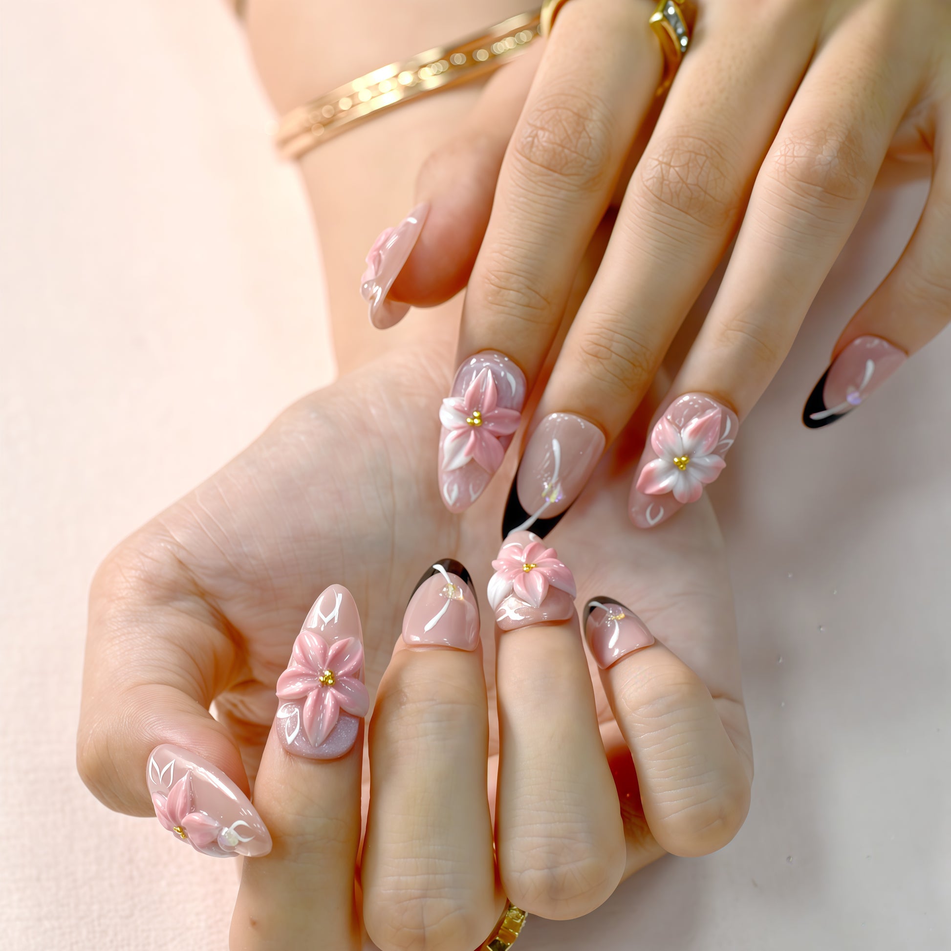 Luxury pink floral press-on nails with 3D flower design, pearl embellishments, and black French tip accents displayed on beige textured background